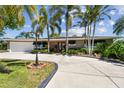 Charming single-story home with a circular driveway and lush tropical landscaping at 650 Poinsettia Rd, Belleair, FL 33756