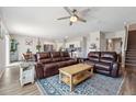 Open-concept living room with modern ceiling fan, plush leather couches, and natural light at 7617 Wallflower Trl, Wesley Chapel, FL 33545