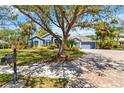Charming blue single-story home with a well manicured front lawn and mature trees at 13136 Peregrin Cir, Bradenton, FL 34212