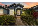 Elegant front entrance with decorative glass doors surrounded by lush tropical landscaping at 13136 Peregrin Cir, Bradenton, FL 34212