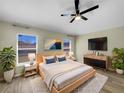 Bright bedroom featuring wood-look floors, a ceiling fan, and a modern dresser with a wall mounted tv at 15452 Long Cypress Dr, Ruskin, FL 33573