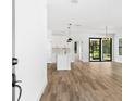 Bright and airy living space with wood-look floors, open to the kitchen with modern pendant lighting at 4080 Baynes Rd, North Port, FL 34288