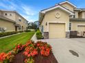 Townhome featuring an attached garage, lush landscaping, and a paver driveway at 8110 Enclave Way # 101, Sarasota, FL 34243