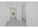 Neutral hallway with gray tile flooring and views into rooms filled with natural light at 7443 S Seagrape Rd, Punta Gorda, FL 33955