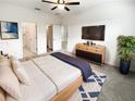 Modern bedroom with a ceiling fan, ensuite bath, walk-in closet, TV, and decorative blue and white rug at 6856 Ripple Pond Loop, Zephyrhills, FL 33541