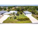 Expansive property featuring a lush green lawn, mature trees, and a matching detached two-car garage at 3215 Peace River Dr, Punta Gorda, FL 33983