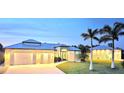 Stunning home with a metal roof, three-car garage, well-manicured lawn, and beautiful landscaping with palm trees at 3215 Peace River Dr, Punta Gorda, FL 33983