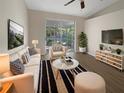 Bright living room with modern decor, a ceiling fan, and a sliding glass door to the lanai at 11823 Derbyshire Dr, Tampa, FL 33626