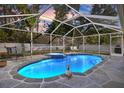 Screened-in pool with beautiful stone surround, attached spa, and green lawn at 3699 N Chamberlain Blvd, North Port, FL 34286