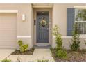 Close-up of the front door featuring a wreath, decorative 'HOME' and 'LOVE' signs, and a stylish exterior light at 8246 Dolphin Bluff Blvd, Wesley Chapel, FL 33545