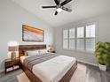 Bright bedroom featuring a ceiling fan, hardwood floors, bedside lamps, and a large window with white shutters at 6122 Osprey Lake Cir, Riverview, FL 33578