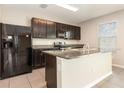 Kitchen featuring dark cabinets, granite countertops, a peninsula, and black appliances at 11807 Myrtle Rock Dr, Riverview, FL 33578