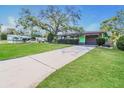 Charming single-story home with a well-manicured lawn and mature trees on a sunny day at 1453 Thames Ln, Clearwater, FL 33755