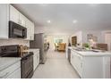 Modern kitchen featuring white cabinets, stainless steel appliances, and an open layout to the dining area at 25290 Puerta Dr, Punta Gorda, FL 33955