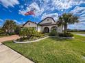 Inviting single-Gathering home with manicured lawn, decorative landscaping, and an American flag at 18743 Coastal Shore Ter, Land O Lakes, FL 34638