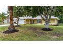 Well-maintained single-story home featuring a lush front yard and mature trees at 201 Chardin Dr, Nokomis, FL 34275
