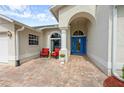 Inviting front entrance with brick pavers, seating area and a bright blue front door at 2444 Grandfather Mtn, Spring Hill, FL 34606