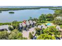Aerial view of condos with a community pool, parking, and serene water views in a lush setting at 1111 N Bayshore Blvd # D6, Clearwater, FL 33759