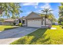 This single-story home features an attached two-car garage and landscaped front yard at 1647 Stable Trl, Palm Harbor, FL 34685