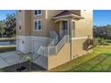 Tan two-story house featuring a multi-car garage, staircase, and a lift for accessibility on a sunny day at 7327 Brightwaters Ct, New Port Richey, FL 34652