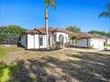 Side view of the single-story home, highlighting stucco siding, screened-in porch, manicured lawn and tropical landscaping at 12402 Creek Edge Dr, Riverview, FL 33579