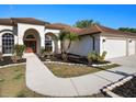 Stunning front exterior showcasing the walkway, stone-lined flowerbeds, manicured lawn, and mature tropical landscaping at 12402 Creek Edge Dr, Riverview, FL 33579