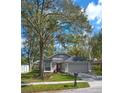 Exterior view of home featuring a two-car garage, a gray roof, gray siding, and a well-maintained yard at 1610 Spinning Wheel Dr, Lutz, FL 33559