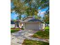 Exterior view of home with gray siding, a gray roof, a gray two-car garage, and a well-kept lawn at 1610 Spinning Wheel Dr, Lutz, FL 33559