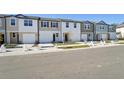 New construction townhomes line a street with sidewalks, manicured lawns, and available homes signs at 11929 Sylvia St, Dade City, FL 33525