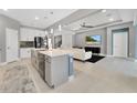 Open white kitchen featuring a central island, stainless steel appliances, and modern finishes at 32554 Silvercreek Way, Wesley Chapel, FL 33545