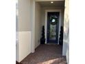 Close-up of front entrance with brick floor, decorative wreath on door, and potted topiaries at 1427 Hyssop Loop, North Port, FL 34289