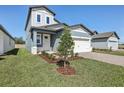 Two-story home with gray siding, white trim, a well-kept lawn, and paver driveway at 1869 Brekey Way, Zephyrhills, FL 33541