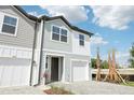 Charming two-story townhome featuring a one car garage, blue siding, and tropical landscaping at 7294 Deer Valley Cir, Tampa, FL 33635
