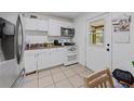 Functional kitchen with white cabinetry, tile floors, and an access door to the outside at 215 Melody Ln, Largo, FL 33771