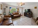 Cozy living room featuring tile flooring, comfortable leather sofas, and a ceiling fan at 215 Melody Ln, Largo, FL 33771