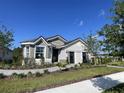 Inviting single-story home showcasing stone details, gray siding, lush landscaping, and a well-manicured front yard at 2718 Wise River Lane, Zephyrhills, FL 33539