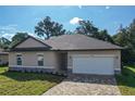 Charming single-story home featuring a neutral color palette, attached two car garage, and patterned paver driveway at 80 Sequoyah Dr, Port Charlotte, FL 33954