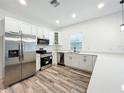Modern kitchen featuring stainless steel appliances, white cabinetry, stone countertops, and wood grain floors at 80 Sequoyah Dr, Port Charlotte, FL 33954