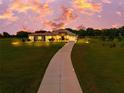 Stately home with a long driveway and lush green lawn, illuminated by landscape lighting at dusk at 6306 Foxbrook Trl, Parrish, FL 34219