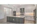 A modern kitchen featuring stainless steel appliances, gray lower cabinets, white upper cabinets, and a central island at 18213 Cresswind Ter, Lakewood Ranch, FL 34211