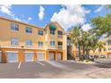 Sunny condo building featuring private garages, stairs to upper units, and lush palm trees at 10764 70Th Ave # 3305, Seminole, FL 33772