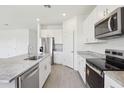 Bright kitchen featuring white cabinets, stainless steel appliances, granite countertops, and wood look tile flooring at 1878 Draughton Dr, Zephyrhills, FL 33541