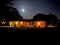 Night view of a single-story home with illuminated landscaping and lovely architecture at 3652 Oak Grove Dr, Sarasota, FL 34243