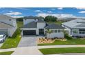 Modern home with a dark garage door, minimalist landscaping, and a perfectly manicured green lawn at 10549 Torchwood Sea Way, San Antonio, FL 33576