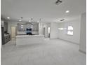 Open concept living room with white marble tile floors and modern lighting, open to kitchen at 2346 Logsdon St, North Port, FL 34287