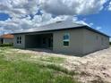 Gray stucco exterior with covered patio, and white trim windows overlooking the backyard at 24462 Cabana Rd, Punta Gorda, FL 33955