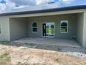 Covered patio features a concrete floor, gray stucco, white trim windows, and a sliding glass door at 24462 Cabana Rd, Punta Gorda, FL 33955