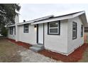 Front exterior view of a one-story house, with a white exterior, black-framed windows, and a newly landscaped yard at 316 21St W St, Palmetto, FL 34221
