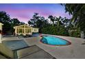 Inviting backyard with a sparkling pool, sunroom, outdoor dining area, and lush tropical landscaping at 913 Tennessee Ln, Sarasota, FL 34234