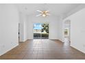 Spacious and bright living room featuring tile floors, a ceiling fan, and large sliding glass doors with lake view at 12511 Lake Vista Dr, Gibsonton, FL 33534